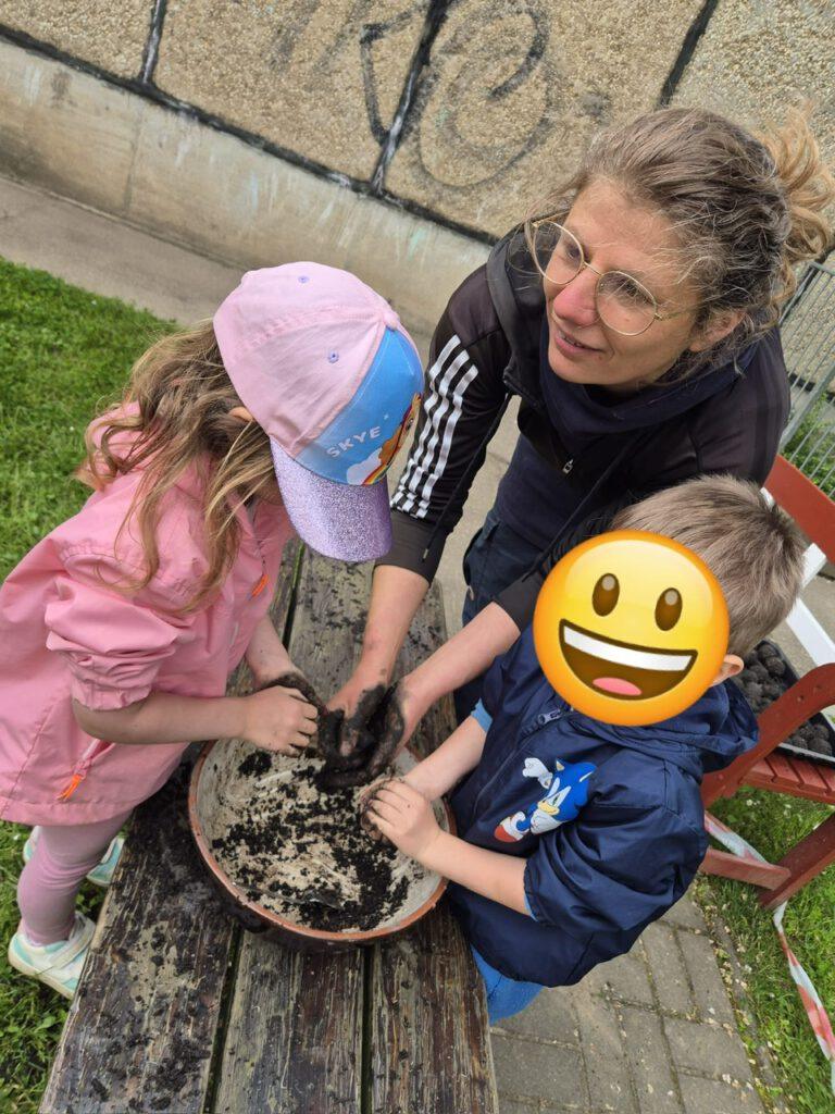 Kinder und Anleiterin formen Seedbombs an einem Tisch in Grünau