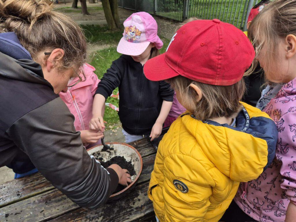 Kindergartenkinder und Anleiterin am Tisch beim Seedbomb-Basteln in Grünau