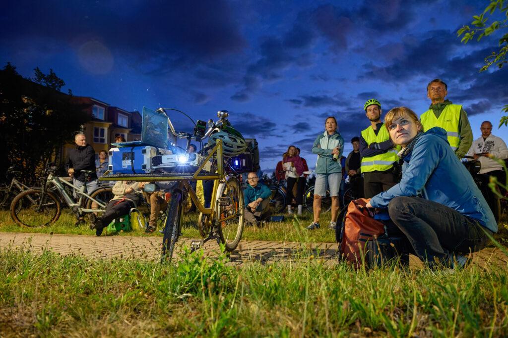 Beamer-Fahrrad und Publikum in der Dämmerung