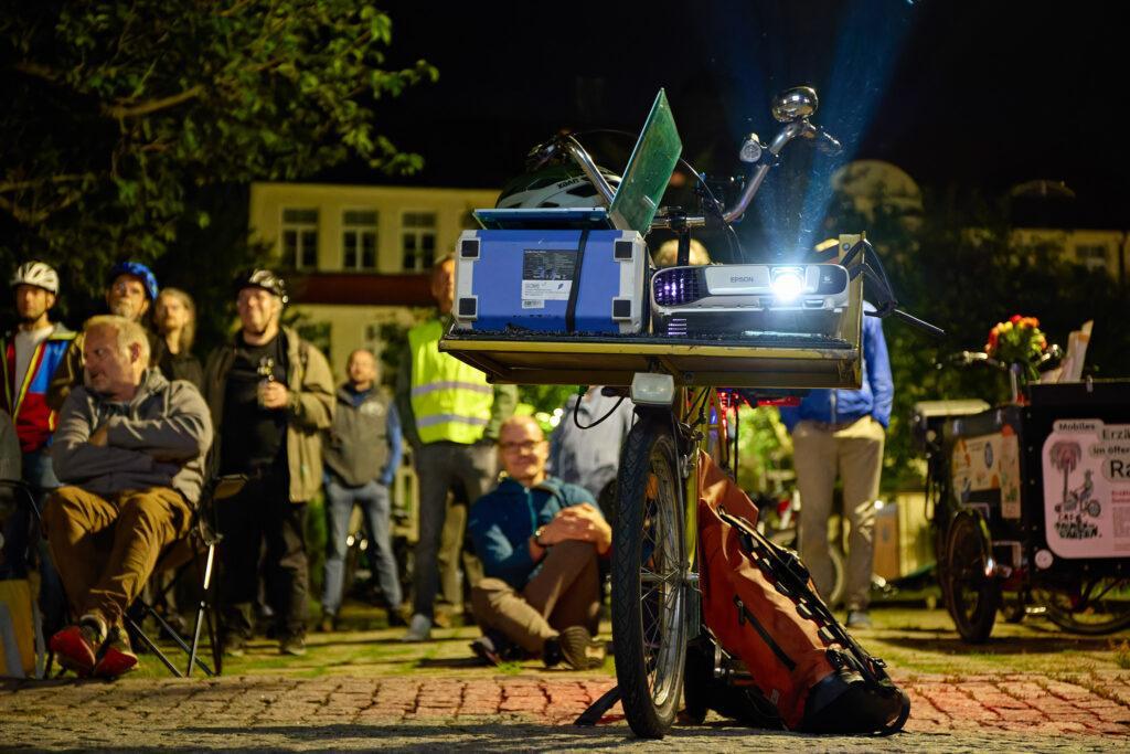 Beamer-Fahrrad mit Publikum im Hintergrund